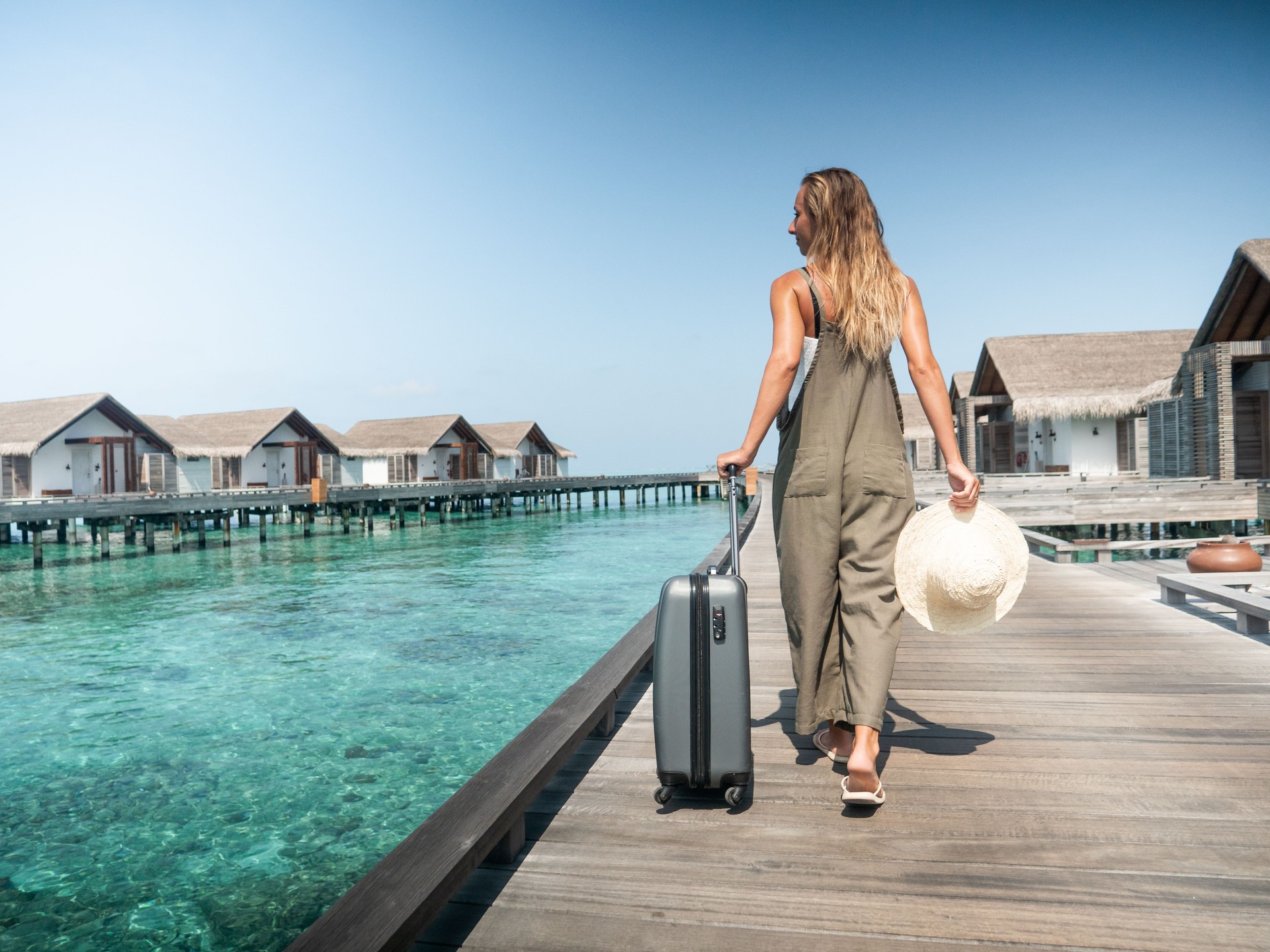 Woman pulls trolley on wooden pier in tropical destination